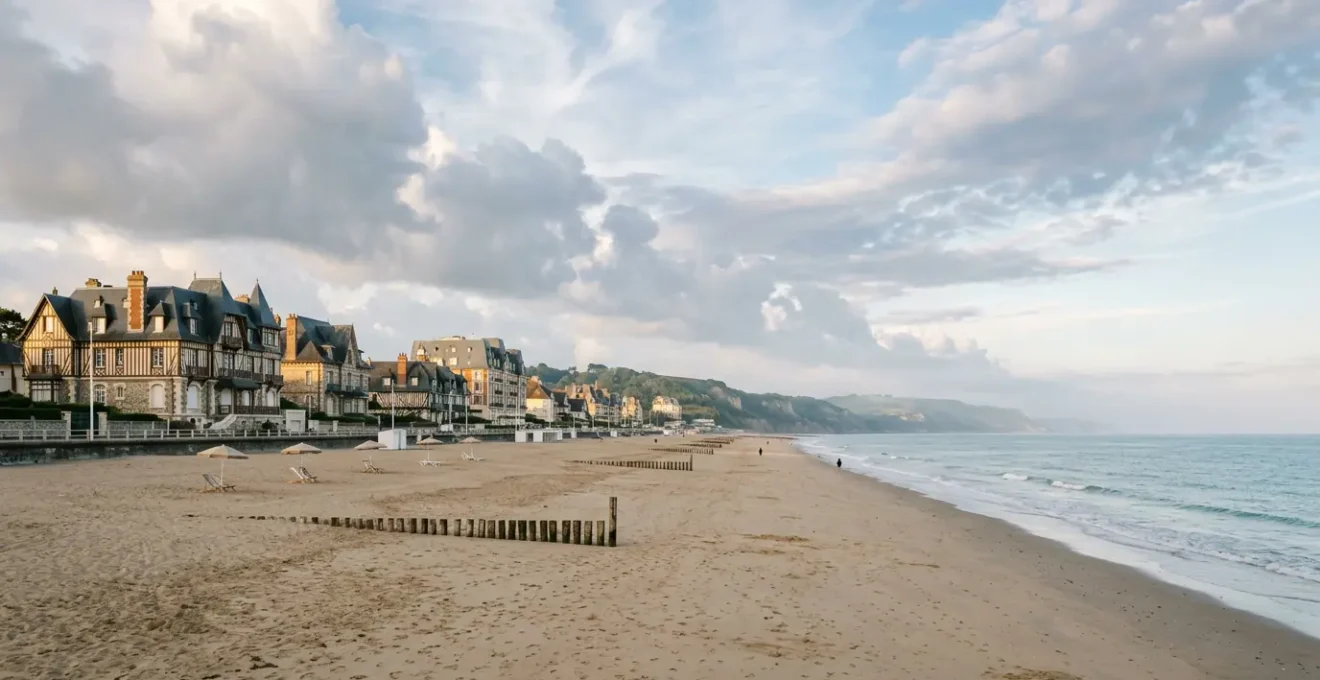 Vue panoramique de la plage normande avec cabines colorées et architecture Belle Époque en arrière-plan