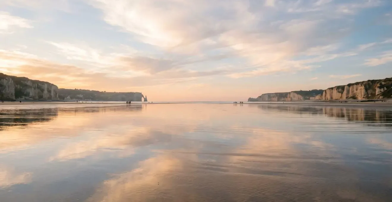 Vue aérienne d'une plage normande à marée basse avec l'estran formant un miroir naturel reflétant le ciel et les nuages